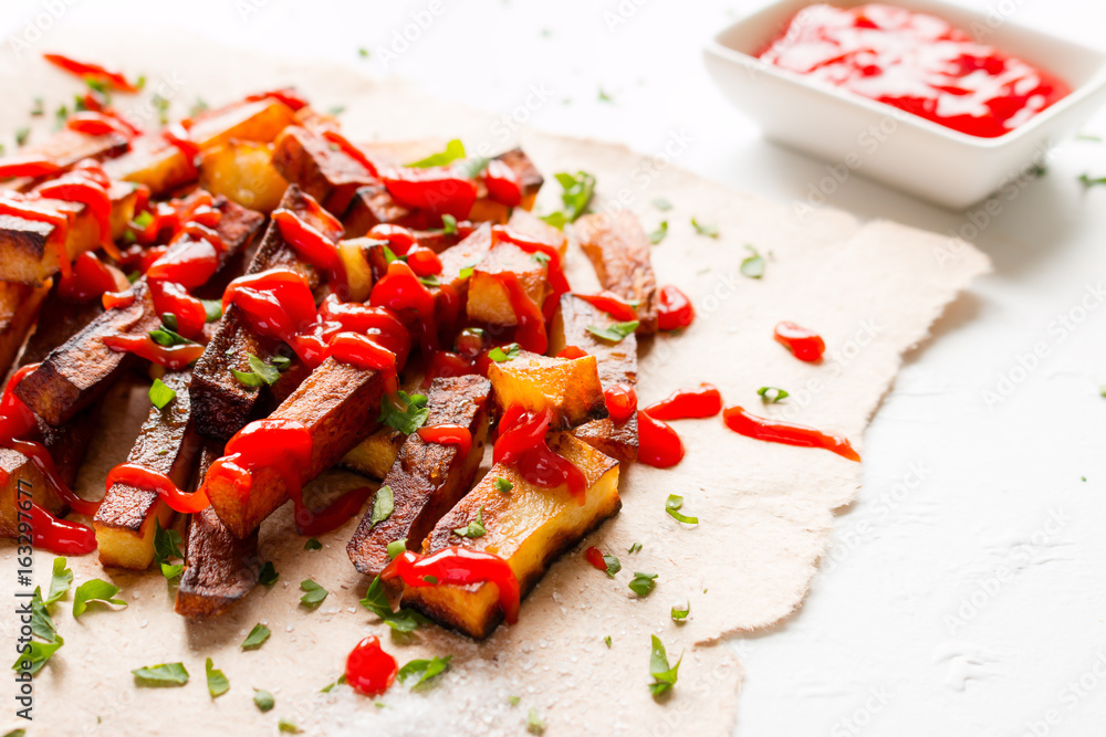 Fried potatoes and ketchup on a white background