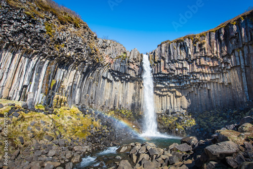 Svartifoss in midday no clounds in Iceland with rainbow