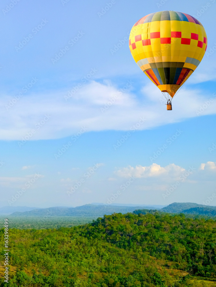 Hot-air Balloon floating in the sky near a rainbow over the mountains. landscape background