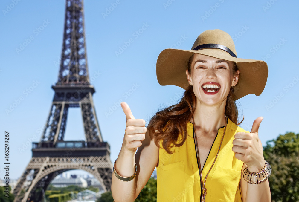 happy woman showing thumbs up against Eiffel tower in Paris