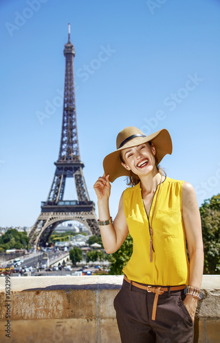 smiling woman in bright blouse against Eiffel tower in Paris © Alliance