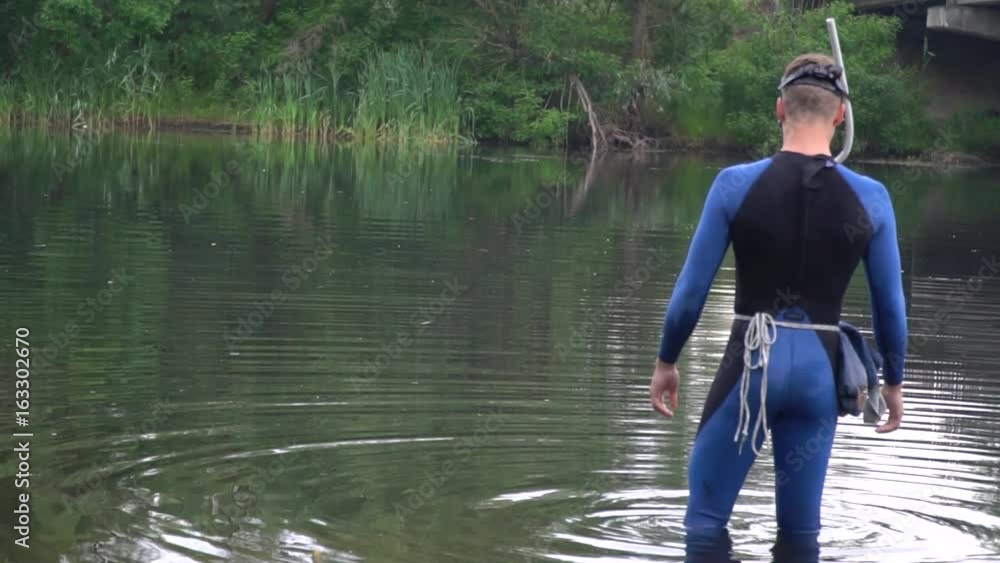 A man in a scuba gear and a mask stands in the river A man in a scuba gear and a mask stands in the river
