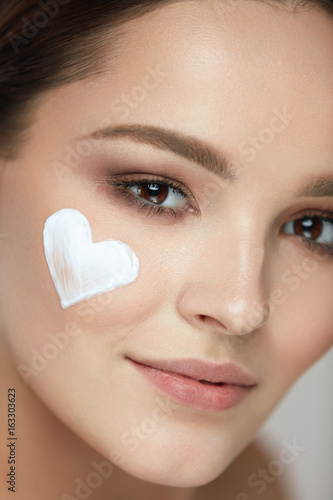 Beautiful Happy Woman With Heart Of Cream On Beauty Face Skin