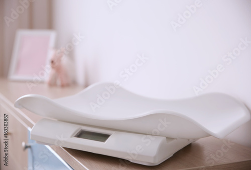 Digital baby scales on table in light room © Africa Studio