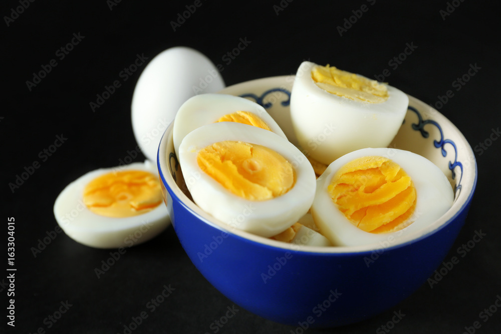 Bowl with sliced hard boiled eggs on black background. Nutrition concept Bowl with sliced hard boiled eggs on black background. Nutrition concept