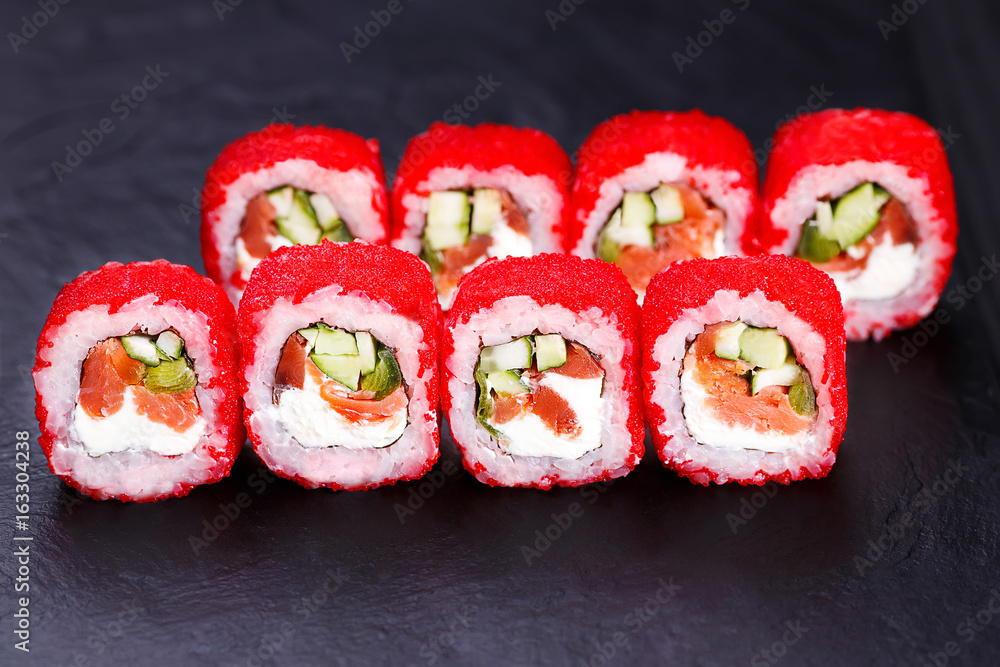 Delicious sushi rolls with red tobiko served on black slate, close up. Japanese traditional and healthy food. Delicious sushi rolls with red tobiko served on black slate, close up. Japanese traditional and healthy food.