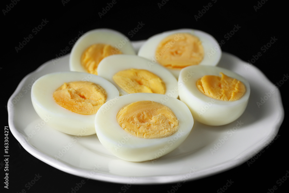 White ceramic plate with hard boiled eggs on black background. Nutrition concept White ceramic plate with hard boiled eggs on black background. Nutrition concept