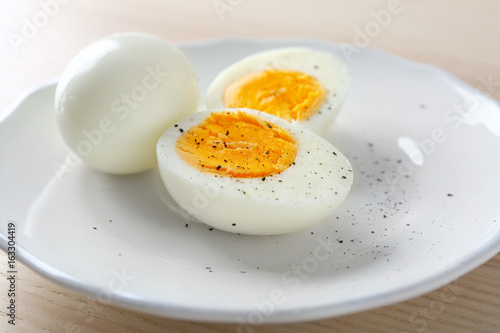 White ceramic plate with hard boiled eggs on light table. Nutrition concept