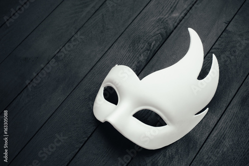 White swan mask on black wooden surface. Empty space.