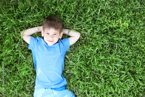 Cute little boy lying on gr...