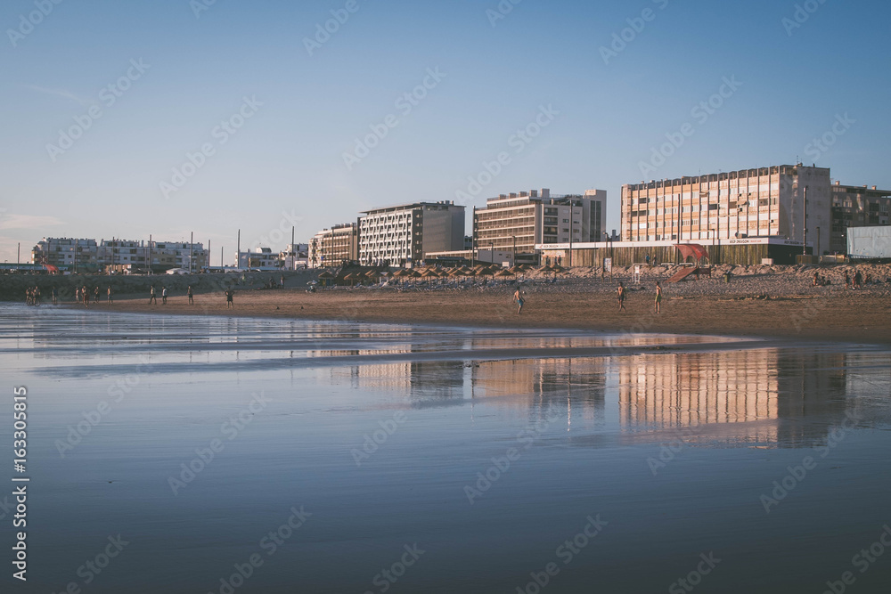 Buildings Mirroring on the sand at Costa da Caparica, one of the best beaches in Lisbon, Portugal