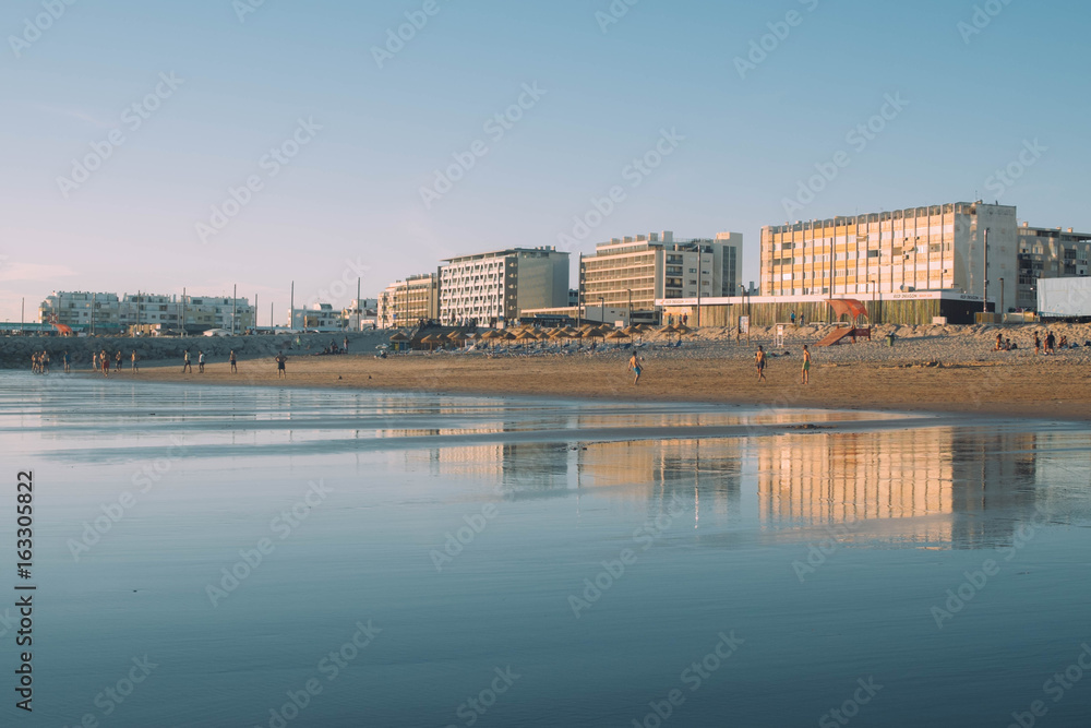 Buildings Mirroring on the sand at Costa da Caparica, one of the best beaches in Lisbon, Portugal