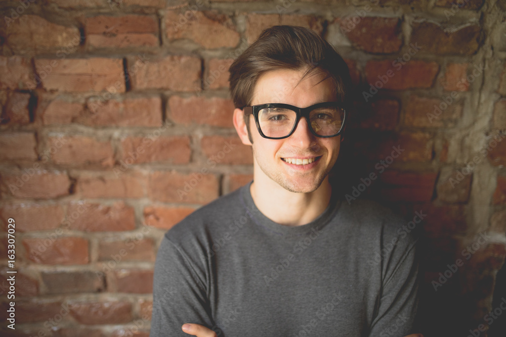 Portrait of a casually dressed young businessman standing with his arms crossed against a brick Portrait of a casually dressed young businessman standing with his arms crossed against a brick
