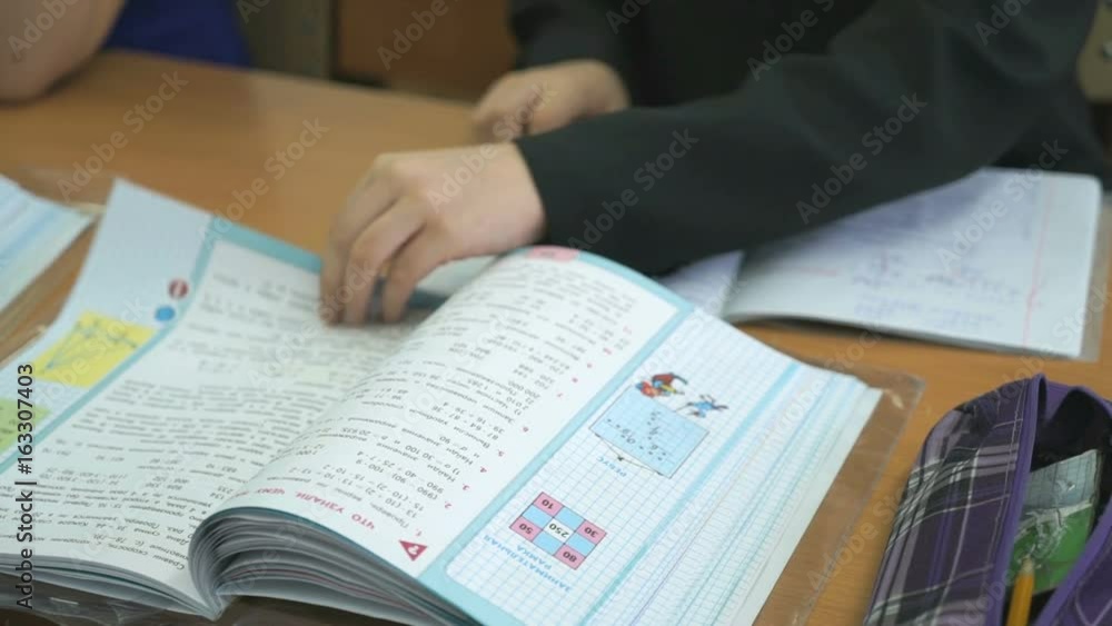 The pupil sitting at school desk flips the pages of the school book The pupil sitting at school desk flips the pages of the school book