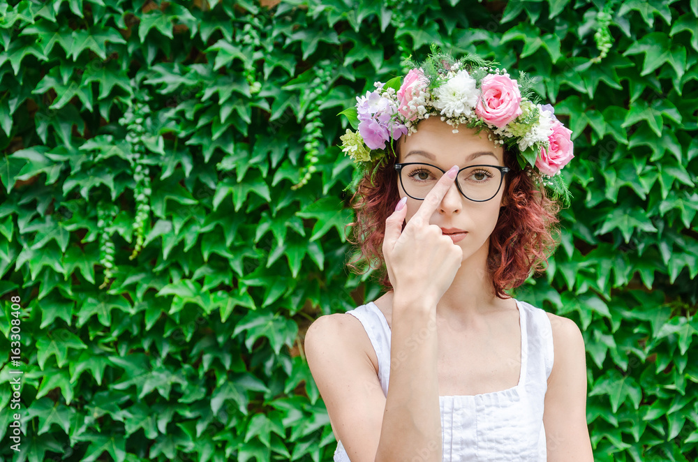 Fototapeta premium woman with wreath on head raises eye glasses