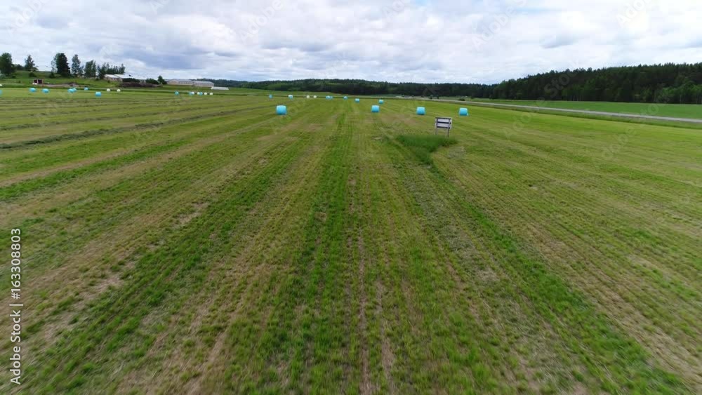 Hay balls, aerial view above a green wheat field, full of white and blue hay balls, on a summer day, in Kemionsaari, varsinais-suomi, Finland Hay balls, aerial view above a green wheat field, full of white and blue hay balls, on a summer day, in Kemionsaari, varsinais-suomi, Finland