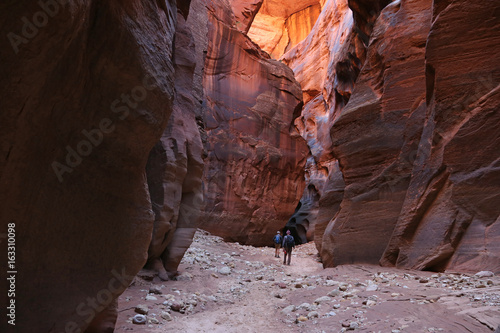 Two hikers dwarfed by Buckskin Gulch, located in southern Utah, it is one of the longest slot canyons in the world..