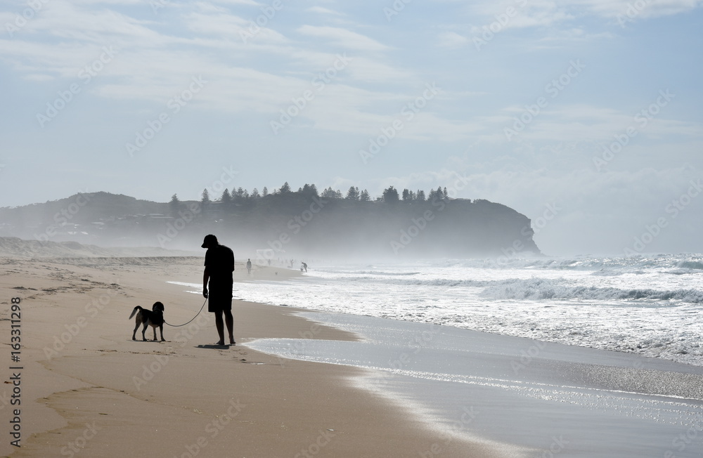 Dog and his owner walking on Belmont beach (Central Coast, NSW, Australia) Dog and his owner walking on Belmont beach (Central Coast, NSW, Australia)