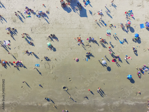 Aerial view beach shoreline on sunny summer day with people bathing, sunbathing, playing volley and relax in Galveston, Texas. Colorful umbrellas, lounge chairs. Holiday maker, summer vacation concept photo