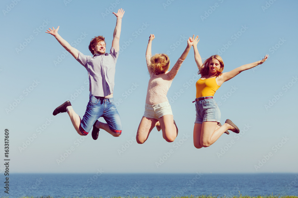 Group of friends boy two girls jumping outdoor