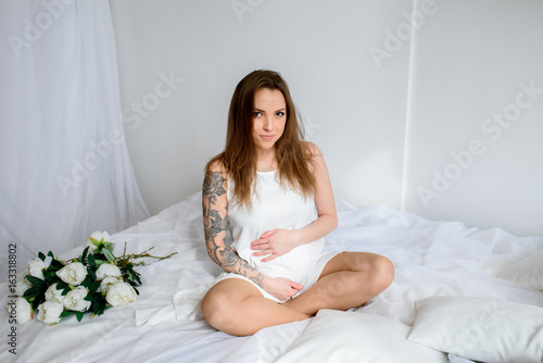 Happy pregnant girl in white dress.