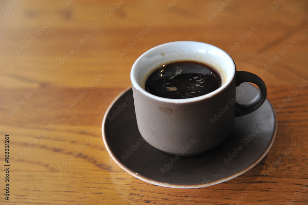 A cup of coffee stands on a brown table in a cafe. A cup of beautiful and fragrant latte with a slice of sugar - a refined sugar and tubules is on the table in a cafe. Cafe inside with visitors and la A cup of coffee stands on a brown table in a cafe. A cup of beautiful and fragrant latte with a slice of sugar - a refined sugar and tubules is on the table in a cafe. Cafe inside with visitors and la