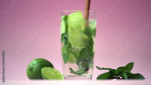 Alcoholic mojito with lime and mint over pink background. 