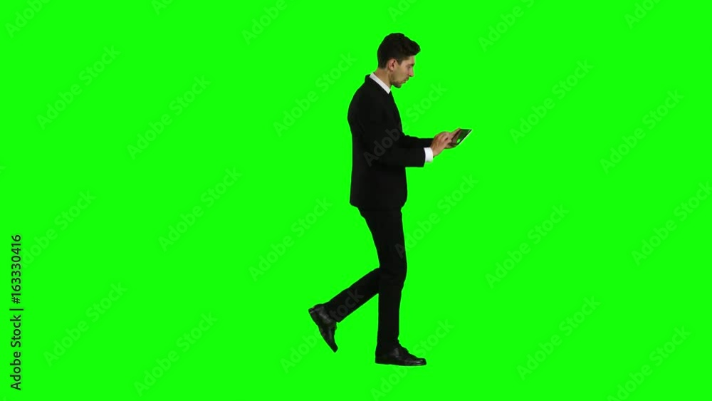 Businessman walks, thumbs a notebook, and makes a selfie. Green screen. Side view Businessman walks, thumbs a notebook, and makes a selfie. Green screen. Side view