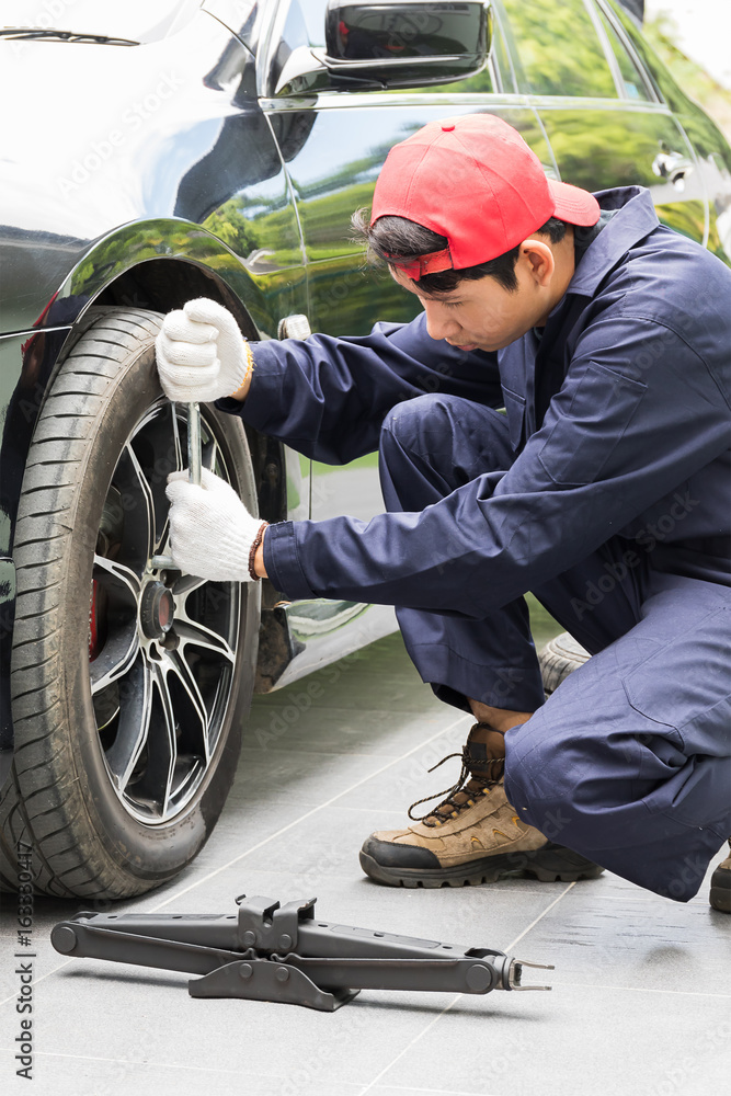 Mechanic replacing lug nuts changing tires on vehicle