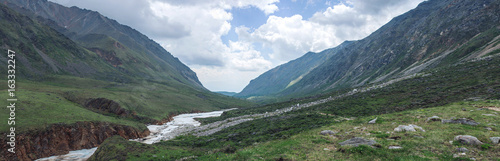 Panorama of mountains covered with green and blue sky with clouds. View of the valley © Artem