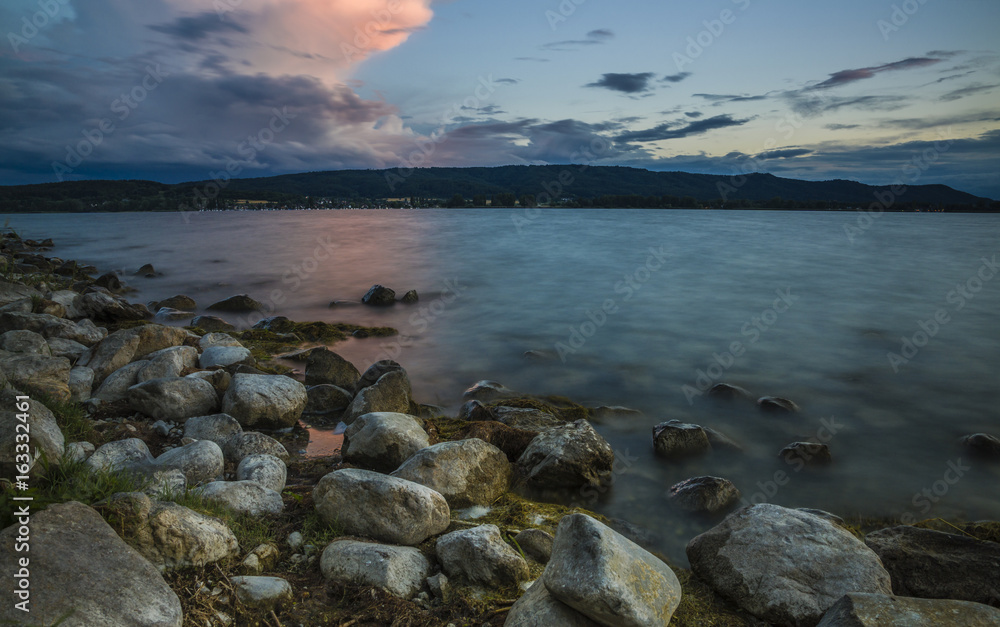 Sonnenuntergang Sommerzeit am Bodensee mit Steinen am Seeufer
