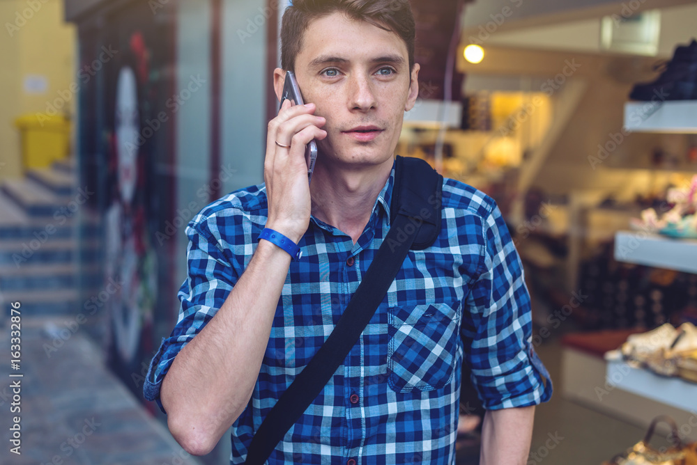 Man traveler with backpack talking on the phone in the background of the street. Man traveler with backpack talking on the phone in the background of the street.