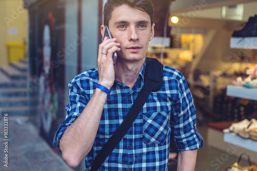 Man traveler with backpack talking on the phone in the background of the street.