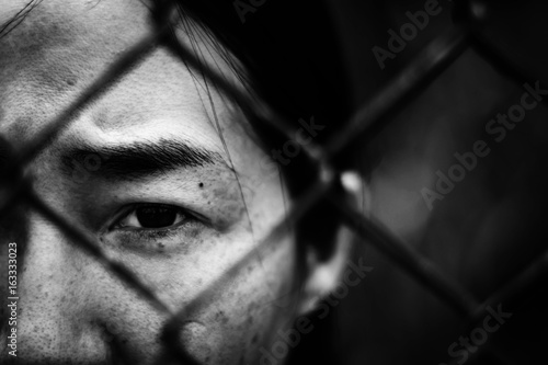 Depressed woman standing behind a fence , abuse concept