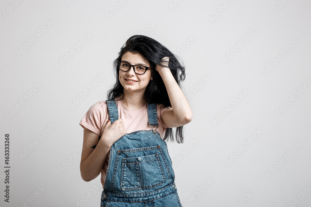 Portrait of smart beautiful brunette girl in eyeglasses with natural make-up, on grey background. Portrait of smart beautiful brunette girl in eyeglasses with natural make-up, on grey background.