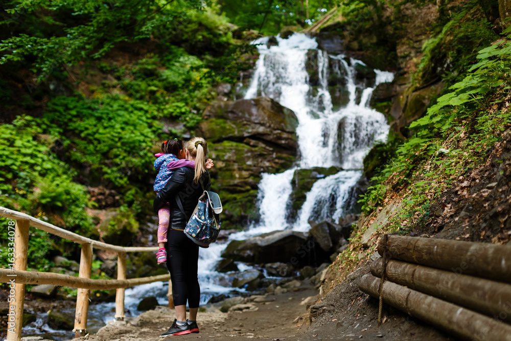 Mother and daughter go camping on a mountain to a waterfall