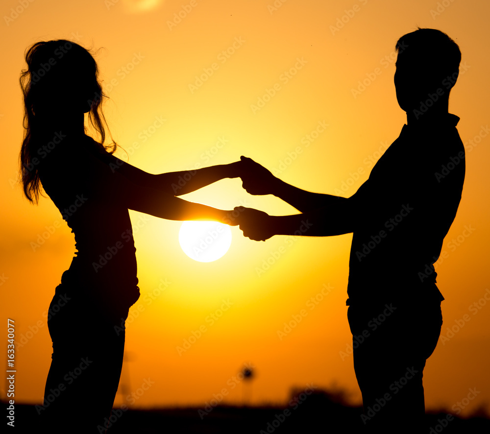 Silhouette of a guy and a girl at sunset