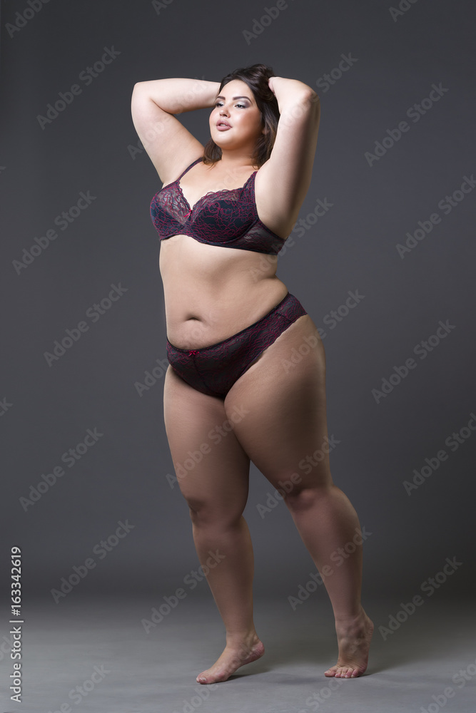 Plus size fashion model in underwear, young fat woman on gray background, overweight female body