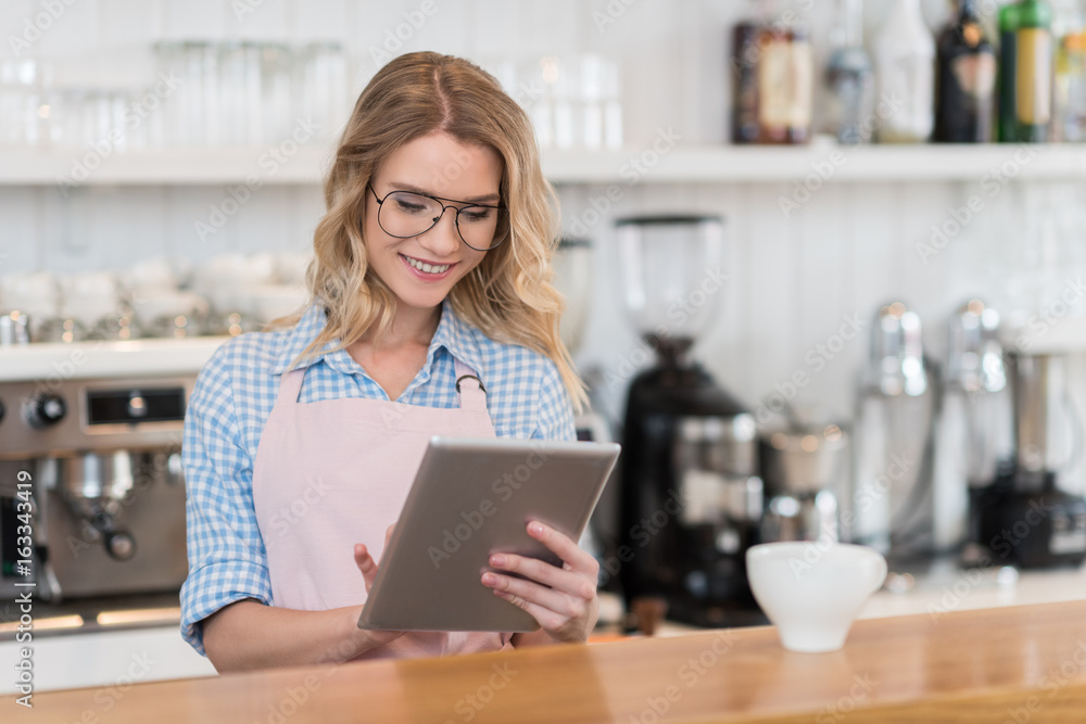 young waitress using digital tablet during work in coffee shop