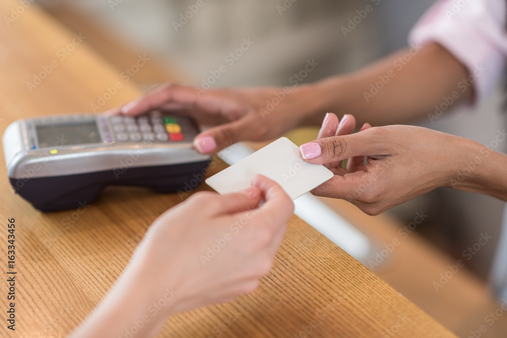 partial view of woman giving credit card to waitress for payment in cafe