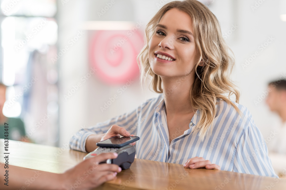 portrait of beautiful smiling woman using smartphone for payment in cafe portrait of beautiful smiling woman using smartphone for payment in cafe
