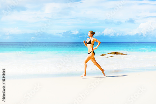 Photo of the young woman jogging on the beach