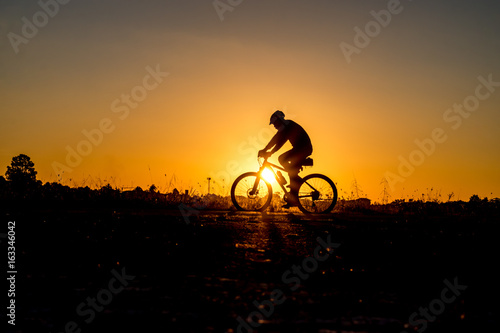 Wallpaper Mural Silhouette of cyclist riding on a bike on road at sunset. Torontodigital.ca
