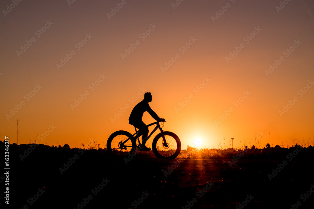 Silhouette of cyclist riding on a bike on road at sunset. Silhouette of cyclist riding on a bike on road at sunset.