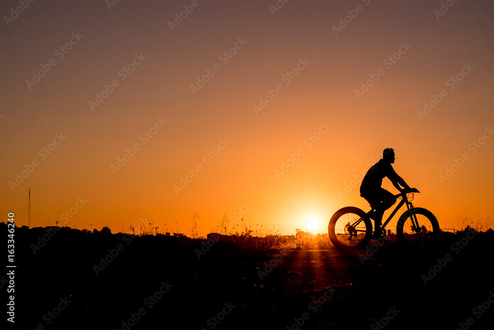 Silhouette of cyclist riding on a bike on road at sunset. Silhouette of cyclist riding on a bike on road at sunset.