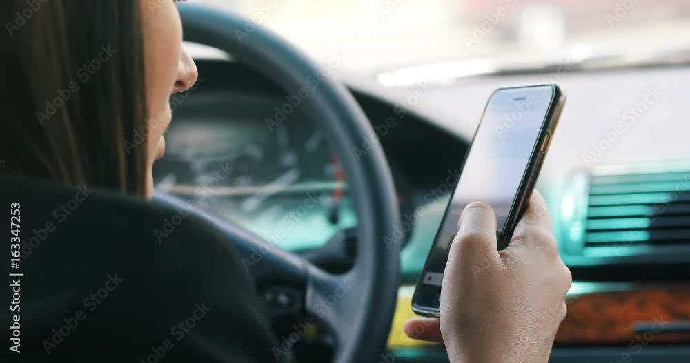 Beautiful woman is sitting in a car. holding a mobile phone and messaging. scrolling social media network apps The lady is looking forward happily. She is smiling auto automobile close up Beautiful woman is sitting in a car. holding a mobile phone and messaging. scrolling social media network apps The lady is looking forward happily. She is smiling auto automobile close up