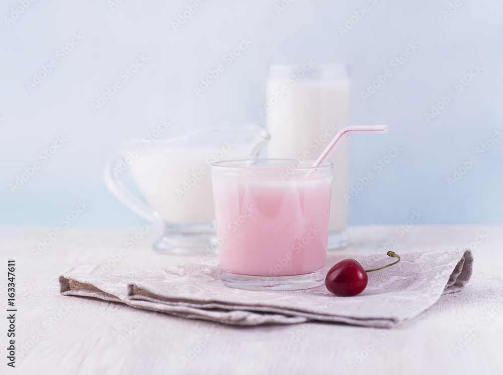 Glasses of milk and delicious milkshake and fresh berries on white wooden table Glasses of milk and delicious milkshake and fresh berries on white wooden table