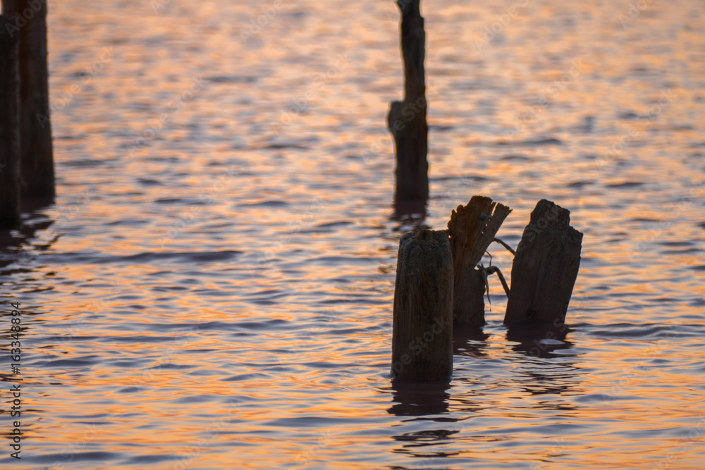 Fototapeta premium Ruined wooden pier on lake / Ruined wooden pier on lake at sunset