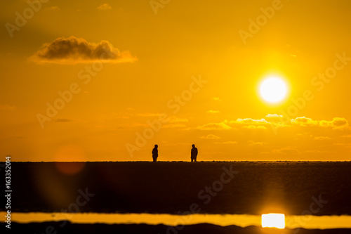 two people facing each other on beach in golden light at sunset