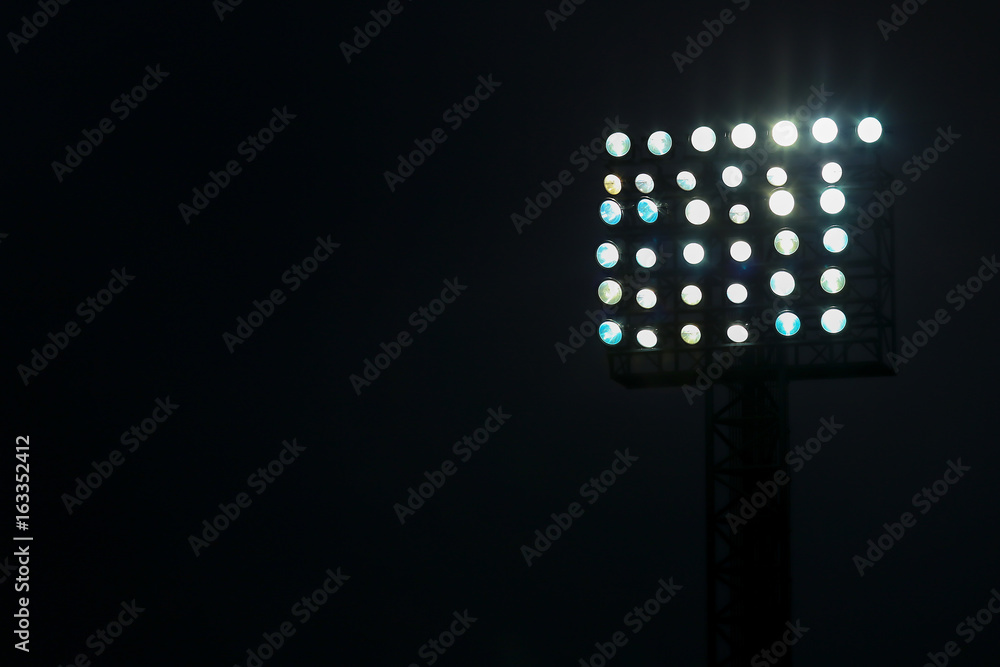 Fototapeta premium Reflektor stadionu piłkarskiego w nocy z ciemnym tłem.